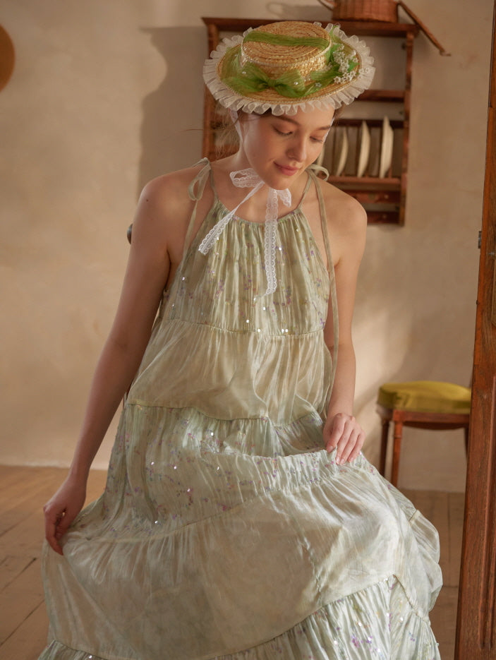 Sitting gracefully, the woman admires the soft shimmer of her green floral dress, styled with a romantic bonnet in a cottagecore setting.