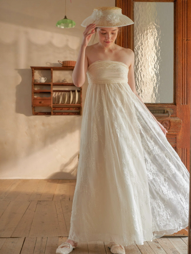 Model poses in a romantic fairycore lace dress with soft pleats and a wide-brim hat, evoking a vintage fairytale atmosphere indoors. 
