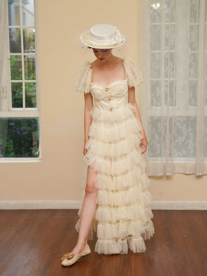 Facing forward in a layered ivory gown, the model showcases romantic princesscore styling with a veiled hat and delicate ruffles throughout.