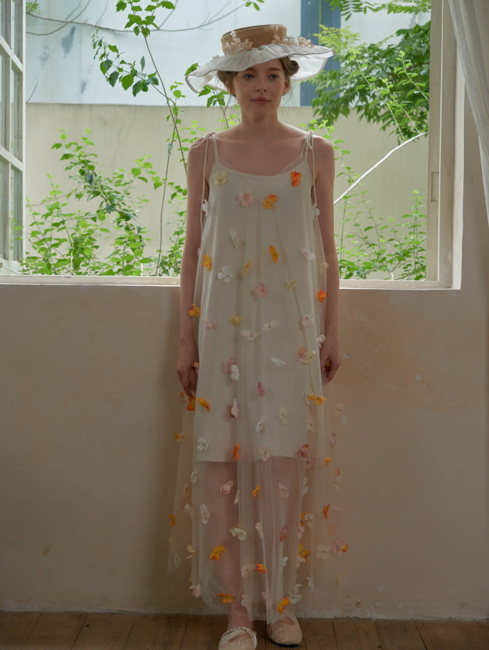 A model stands still in a long sheer floral dress, framed by soft natural light, embodying a calm and romantic fairycore silhouette.