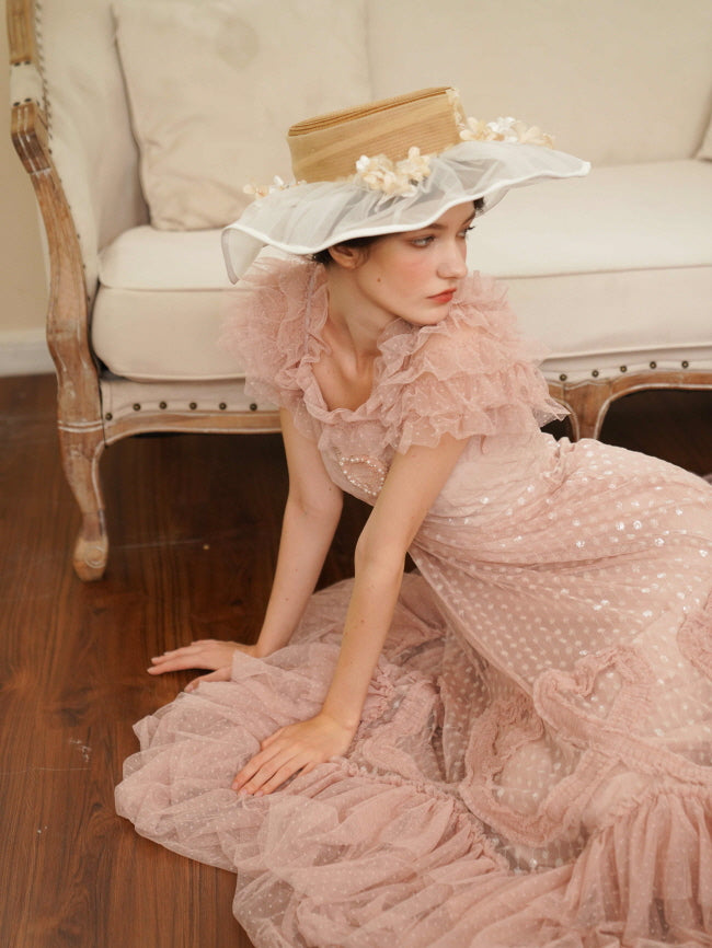 Model poses on the floor in a pink tiered tulle dress with ruffle sleeves and heart embellishment, evoking a dreamy vintage cottagecore mood.