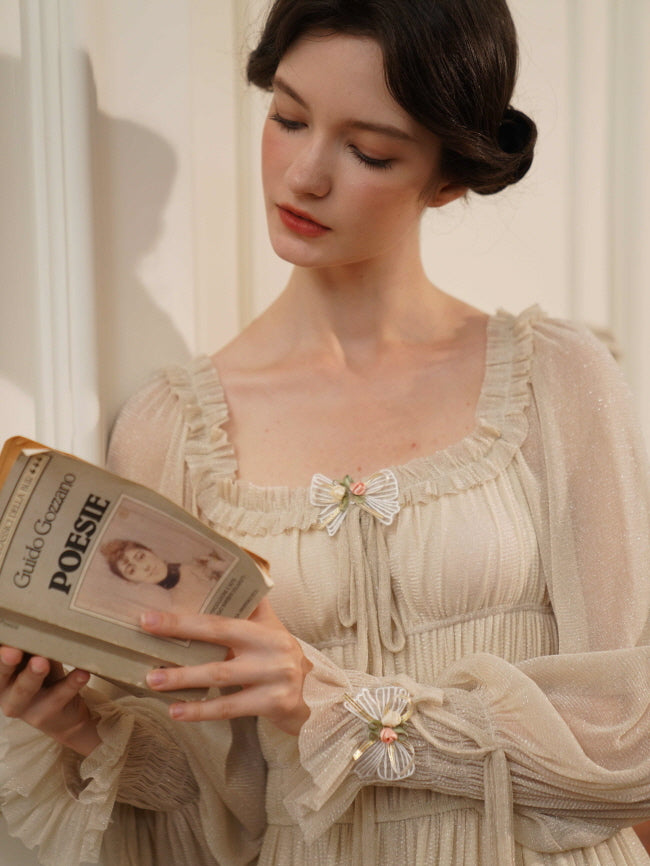 A woman in a soft cream dress with ruffled neckline and ribbon florals reads a vintage poetry book, embodying romantic cottagecore charm.