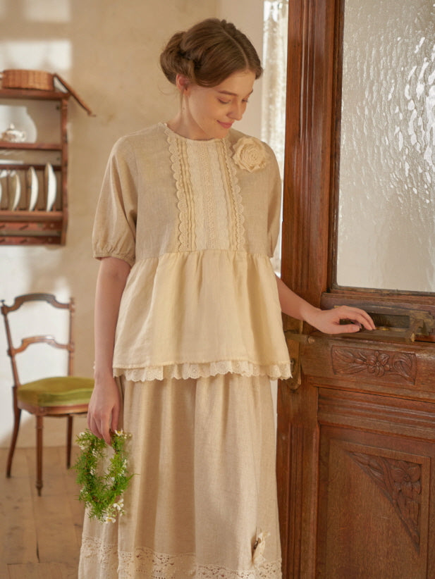 A soft cottagecore outfit with a lace-trimmed beige blouse and long skirt, styled with a green floral wreath in a cozy vintage interior.