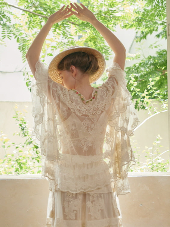 Arms raised gracefully, the model reveals the intricate embroidery and scalloped lace of a romantic fairycore-inspired mesh robe.