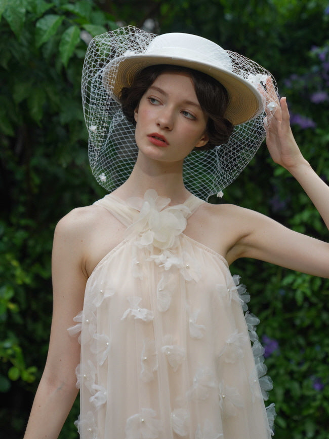 Close-up of a model wearing a delicate beige tulle dress and a vintage white hat with a net veil, capturing a soft fairycore elegance.