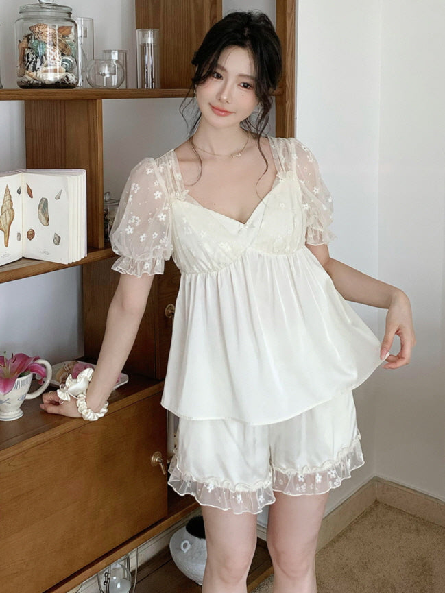 A woman wearing a cream fairycore loungewear set with sheer puff sleeves and floral embroidery, standing in a cozy vintage-style interior.