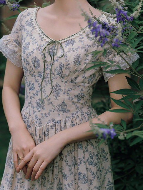 Close-up of a delicate blue floral dress featuring lace trim and a charming bow-tie neckline, capturing a soft, cottagecore-inspired aesthetic.