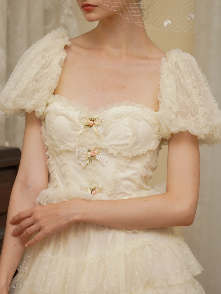 Close-up of an ivory dress bodice with puff sleeves and ribbon floral details, highlighting vintage textures and romantic princesscore charm.