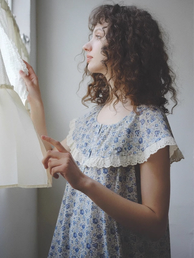 A young woman in a floral lace-trim nightgown gently pulls back the curtain, bathed in soft light for a serene cottagecore morning moment.