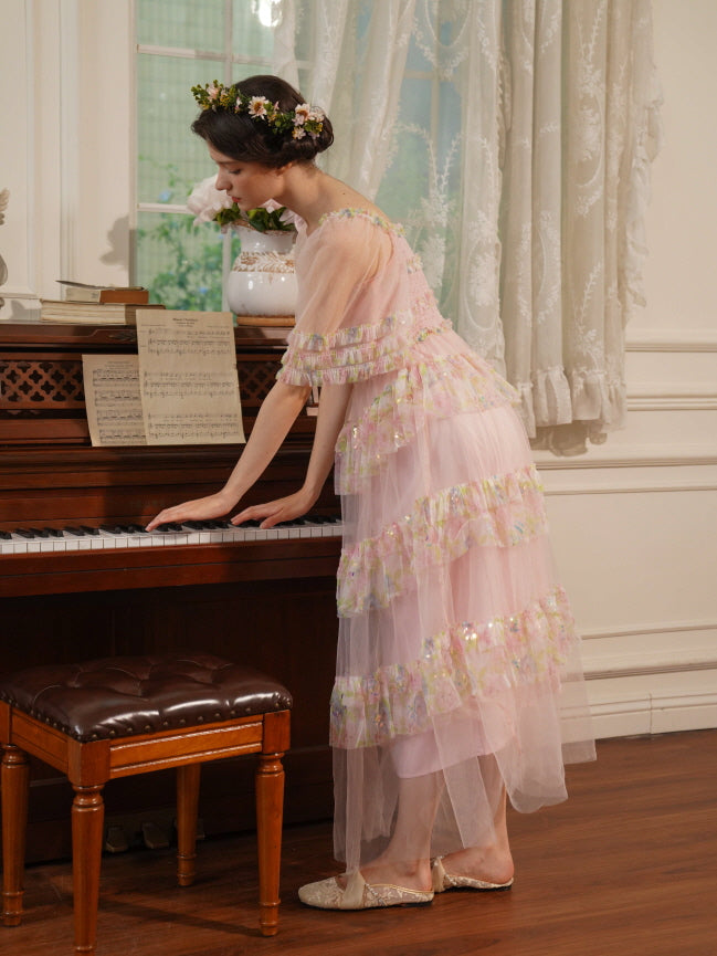 Side view of a woman in a pink ruffle fairycore dress gently leaning on a piano, styled with a floral crown in a soft romantic setting.