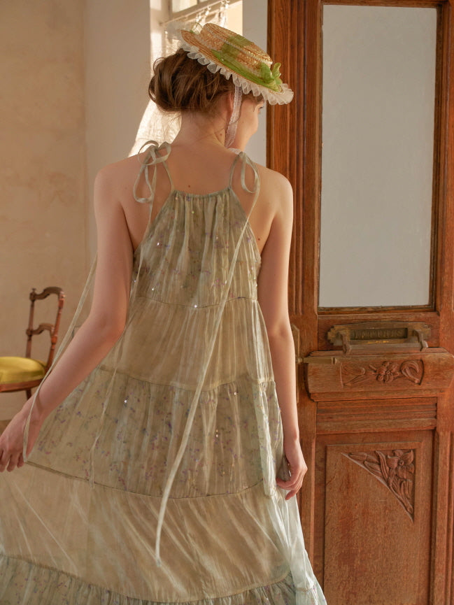 Back view of a woman in a sparkly green halter dress with tie straps, walking gracefully in a sunlit cottagecore interior.