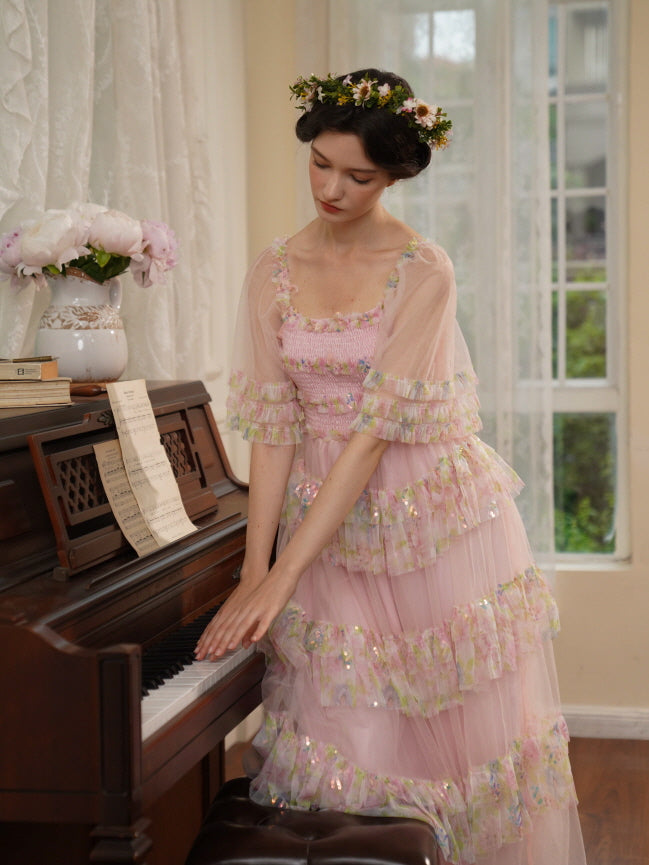 A model in a layered pink tulle dress softly touches piano keys, surrounded by sheer curtains and peonies in a dreamy princesscore scene.