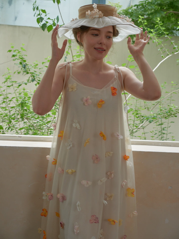 Smiling under a wide-brimmed flower hat, the model gestures playfully in a dreamy embroidered mesh dress with fairytale charm.