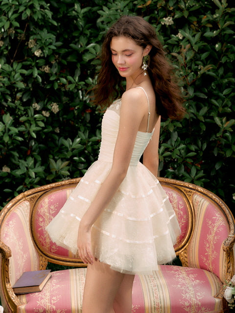 A young woman in an ivory layered mini dress poses in profile, the delicate tulle and fitted bodice reflecting a soft princesscore silhouette.