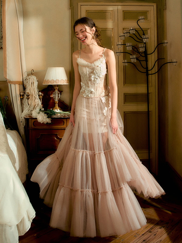 Smiling gracefully in a vintage-inspired room, the model wears a dreamy blush tulle gown with delicate lace flowers, radiating fairytale elegance and soft princesscore style.