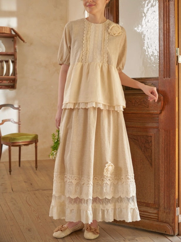 Styled in a romantic cottagecore outfit, the woman gazes softly while wearing a lace-trimmed top and vintage-inspired long skirt.