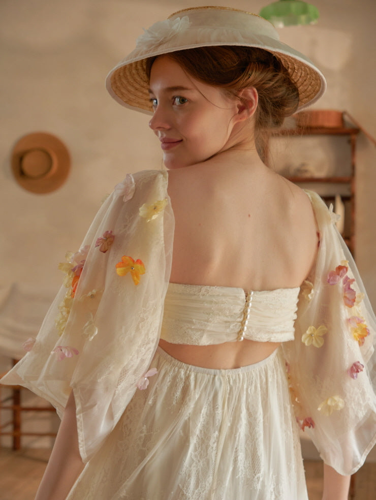 Model turns slightly with a gentle smile, revealing the back details of a romantic ivory lace dress with floral embroidered mesh sleeves, perfect for a fairycore daydream.