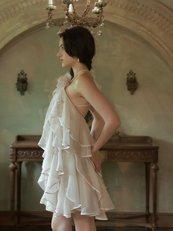 A side profile view of the model in a fairycore ruffle mini dress, featuring delicate straps and a graceful silhouette under a vintage chandelier.