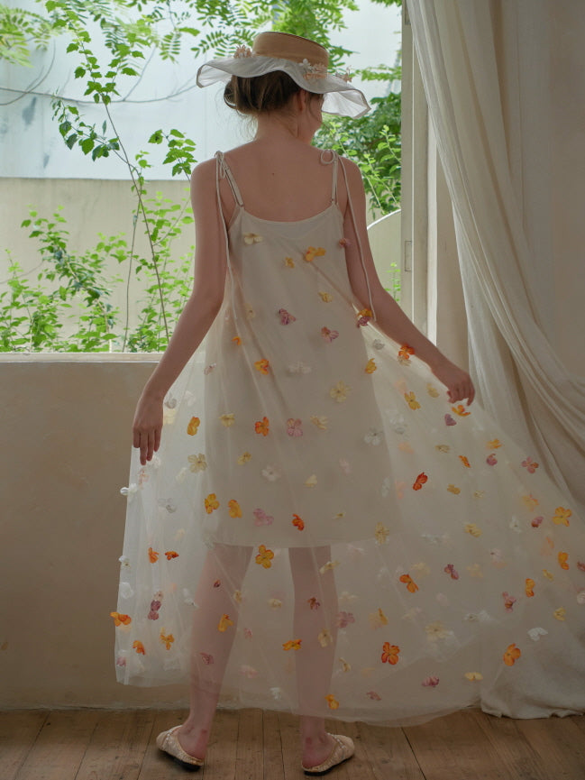A back view of a flowing embroidered mesh dress with vibrant flower appliqués, twirling softly in a vintage fairycore setting.