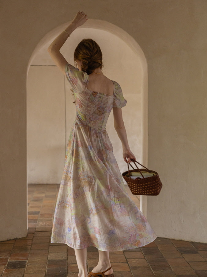A woman twirls gracefully, holding a woven basket, as the flowing pastel floral dress moves with her, evoking a dreamy, fairytale aesthetic.