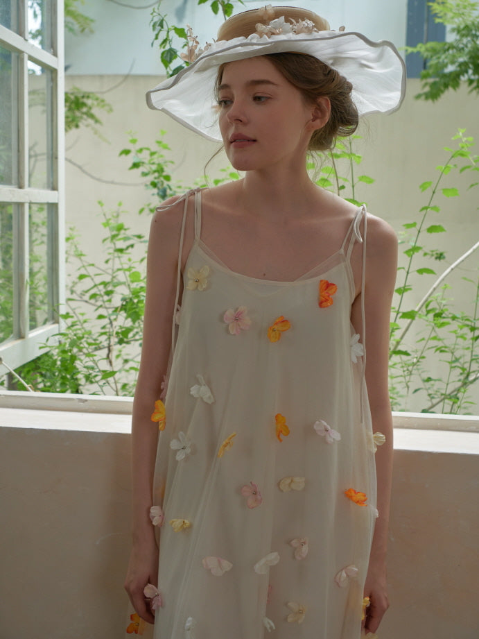 The model gazes softly out the window in a fairytale mesh dress with pastel floral details, blending elegance with a fairycore aesthetic.