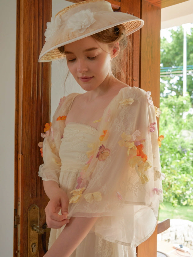 Wearing a vintage-inspired floral dress with sheer petal sleeves, the model softly looks down, embodying a fairycore moment in an idyllic garden setting.