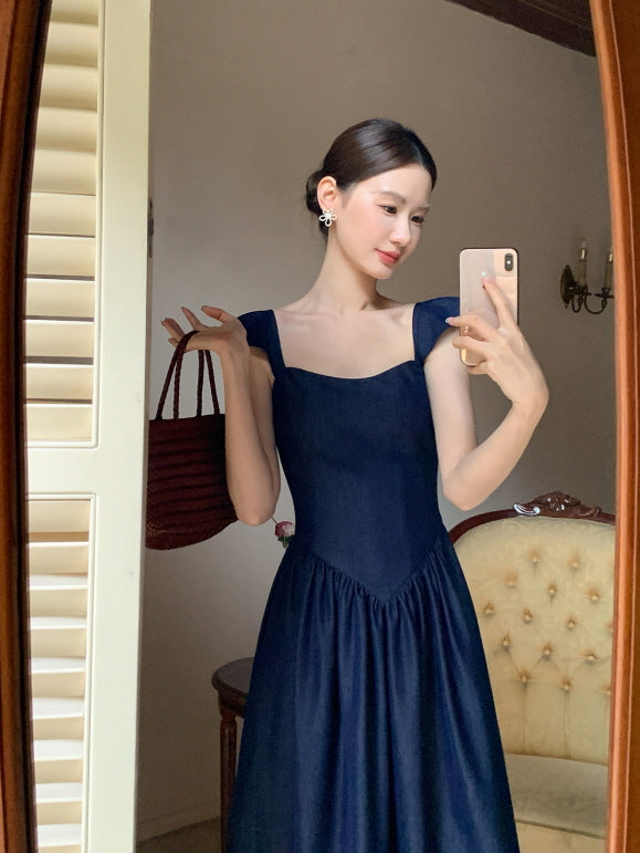 A woman takes a mirror selfie in a navy princesscore dress with structured bodice and flutter sleeves, radiating a soft fairytale elegance.