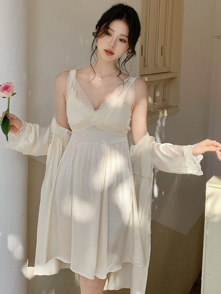 Model wearing an ivory loungewear slip dress with romantic lace trim, framed by floral shadows and soft daylight in a cottagecore setting.