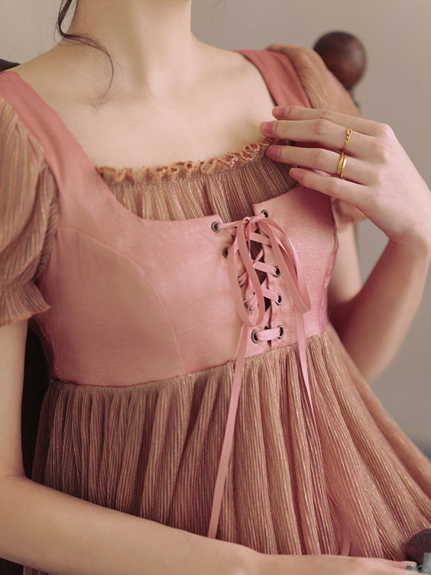 Close-up of the lace-up bodice in soft pink satin, adorned with delicate ribbons and textured pleats, capturing a romantic, vintage-inspired look.