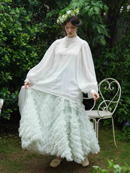 Dressed in a flowing pastel skirt and puff-sleeve blouse, the model poses gracefully outdoors, capturing a vintage-inspired princesscore mood.