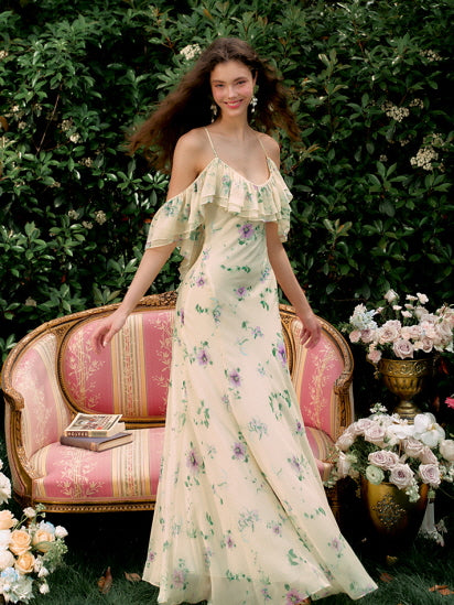 Relaxing gracefully on garden grass, the model gazes softly in a ruffled off-shoulder floral dress, capturing dreamy fairycore elegance.