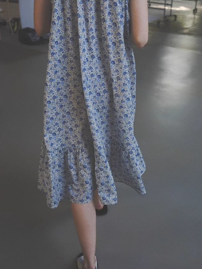 Back view of a flowy blue floral nightgown as the model walks barefoot indoors, capturing a dreamy and relaxed cottagecore aesthetic.