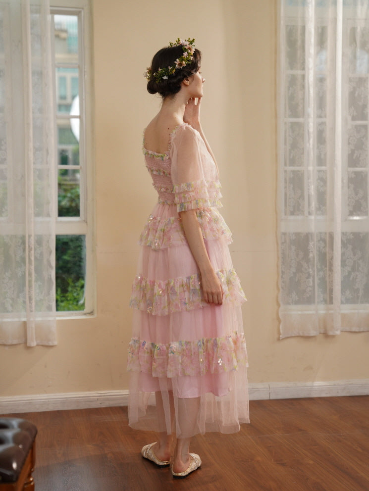 Side view of a model in a pastel pink layered dress with puff sleeves and sequin ruffles, styled in a romantic princesscore room.