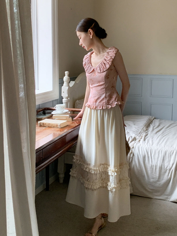 Standing by the window in a soft pink ruffle blouse and ivory lace skirt, the model creates a peaceful romantic cottagecore mood.