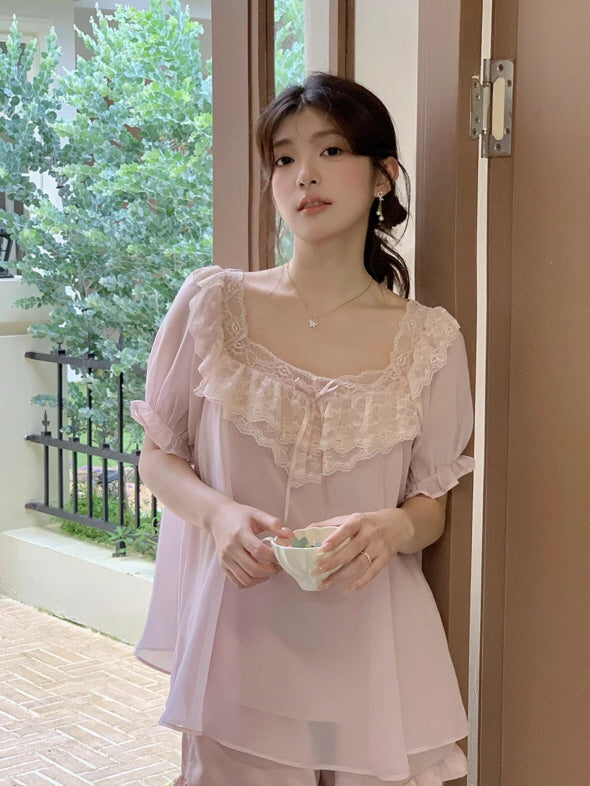 Woman in a fairy pastel pink pajama set with lace trim and puff sleeves, standing by an open door and holding a teacup in a serene cottagecore scene.