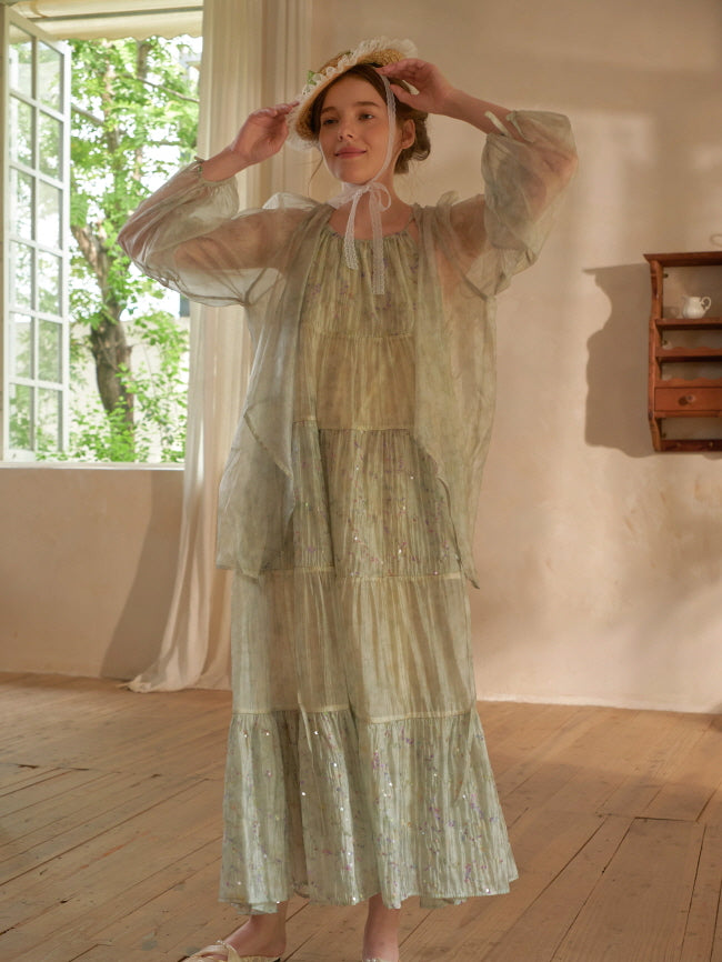 Smiling beneath a lace bonnet, the woman lifts her arms in a light green tiered dress with a sheer overlay, exuding dreamy fairycore charm.