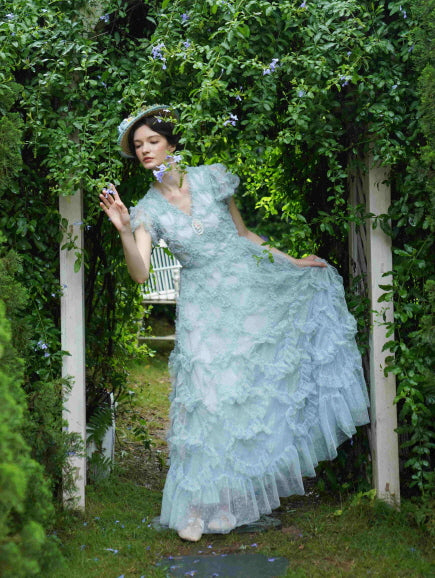 Under a leafy archway, the model gently leans forward in a floral ruffle gown, capturing a whimsical fairytale moment in a serene fairytale garden.