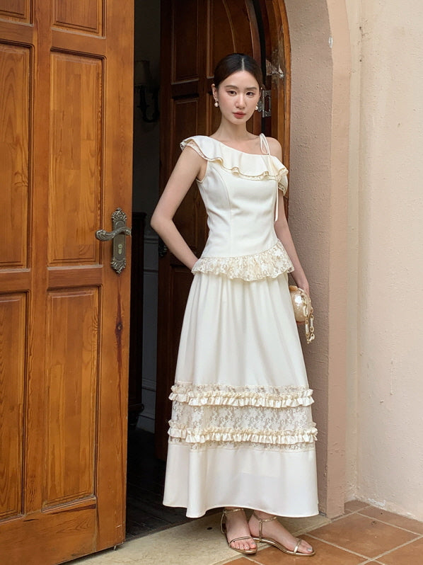 Wearing a cream one-shoulder top with ruffle details and a layered lace skirt, the model stands by a wooden doorway in a fairytale outfit.