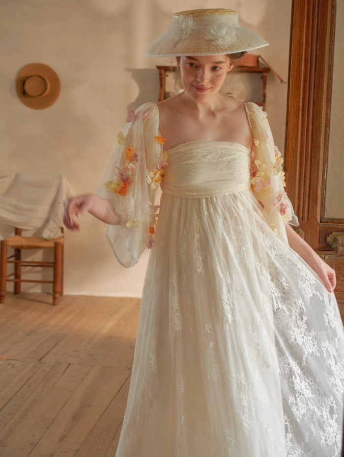 The model stands gracefully in a soft cream strapless lace dress with 3D floral appliqué sleeves, evoking a dreamy fairycore charm.