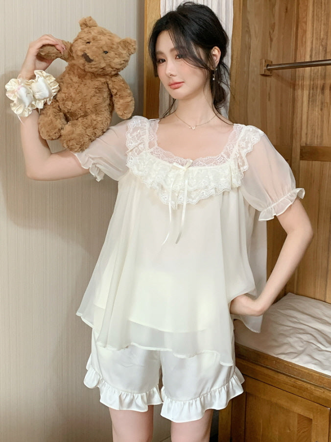 A woman poses with a cute teddy bear, wearing a delicate ivory pajama set with layered chiffon and lace details, styled in a soft coquette mood.